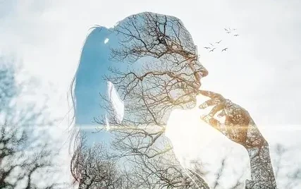 Silhouette de femme avec un paysage d’arbres en transparence, symbolisant la libération du doute et du déni de soi